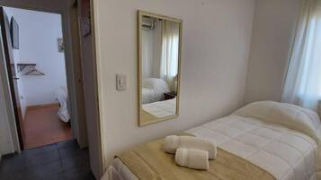 Habitación de hotel con cama, espejo y puerta que da a otra habitación.