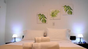 A hotel room with a bed, two bedside lamps, and three framed plant paintings on the wall. - EMILIA HOTEL (Rosario)