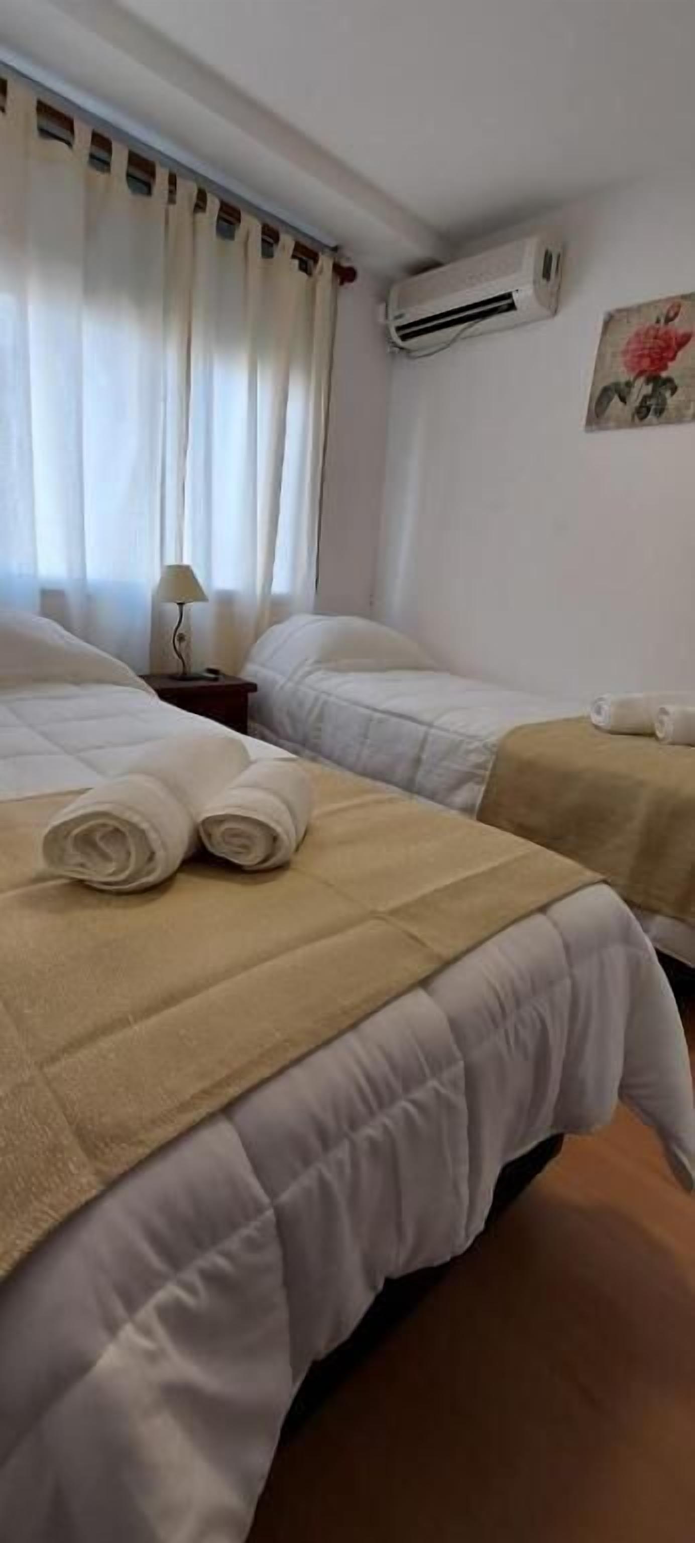 Camera d'albergo con due letti, un comodino con una lampada, un condizionatore d'aria e un quadro appeso al muro.