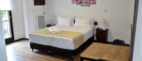 Un dormitorio con cama, mesitas de noche, escritorio y una silla.