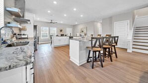 Une cuisine spacieuse dotée d’un îlot central, de meubles blancs et d’un plancher en bois.