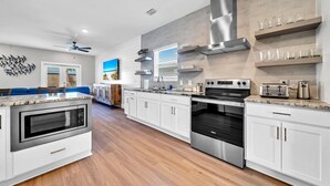 Une cuisine moderne avec des armoires blanches, des appareils en acier inoxydable et un plancher en bois.