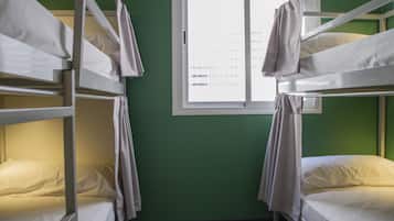 Une chambre de dortoir avec des lits superposés, une fenêtre donnant sur un beau paysage et un mur végétal.