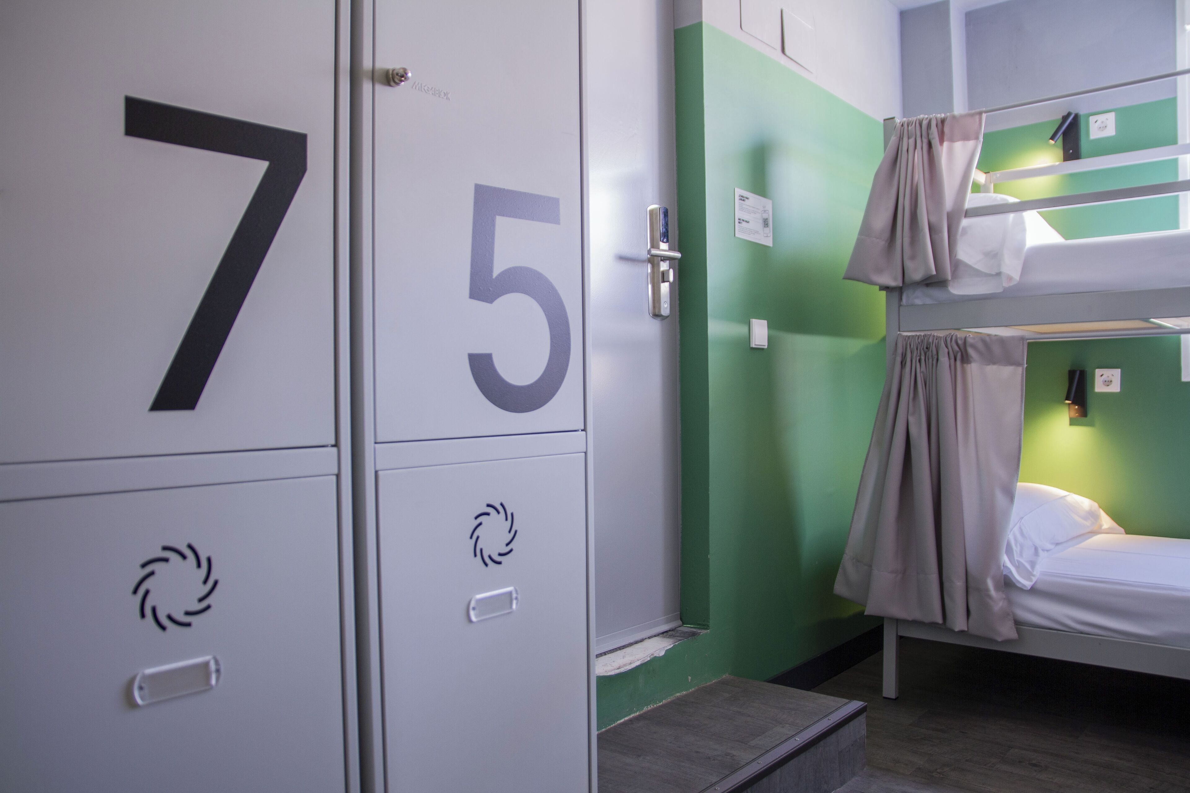 A bunk bed with a curtain, a green wall, and a door with the number 5.