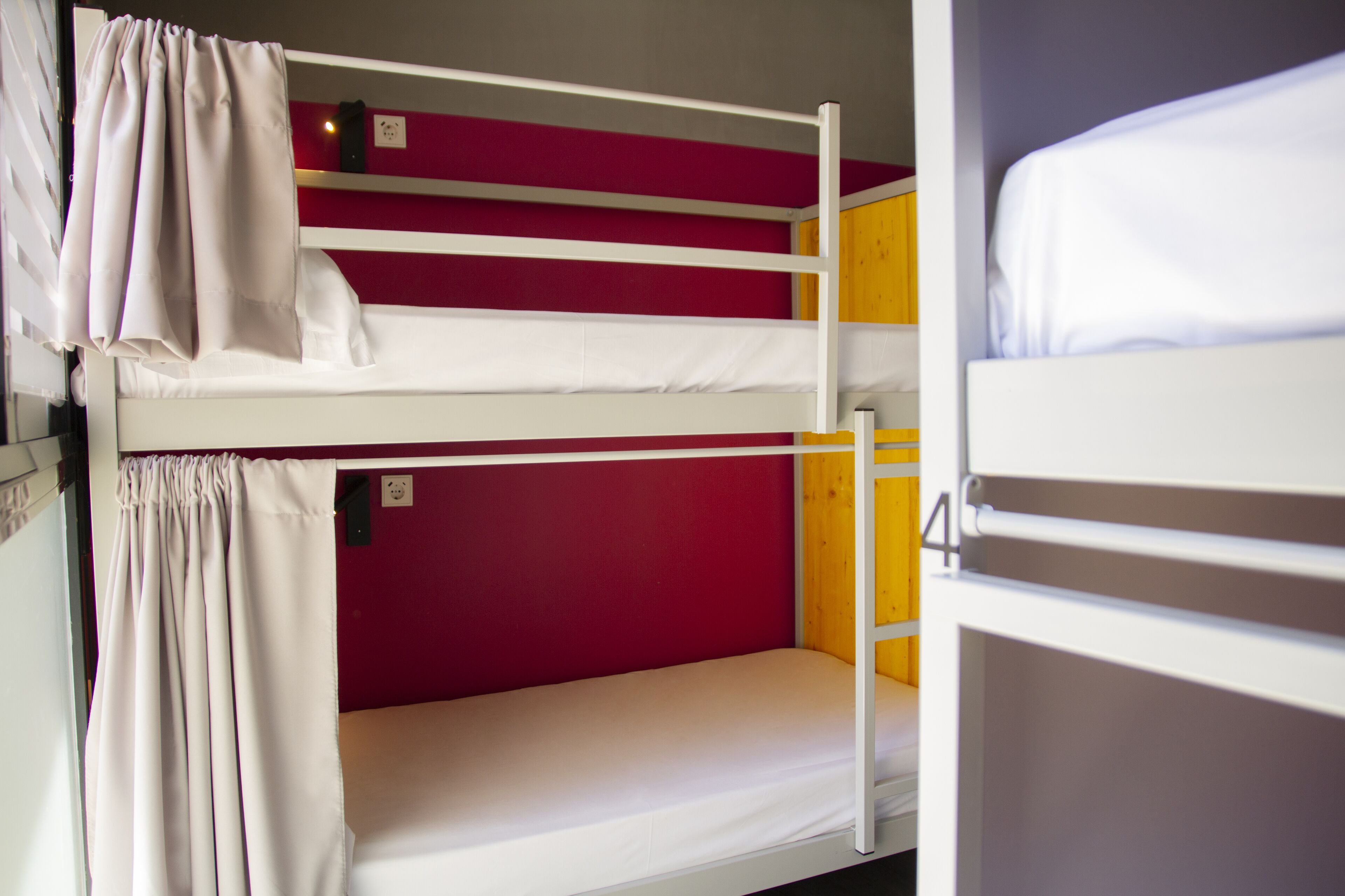 A bunk bed with a red wall and a yellow door.