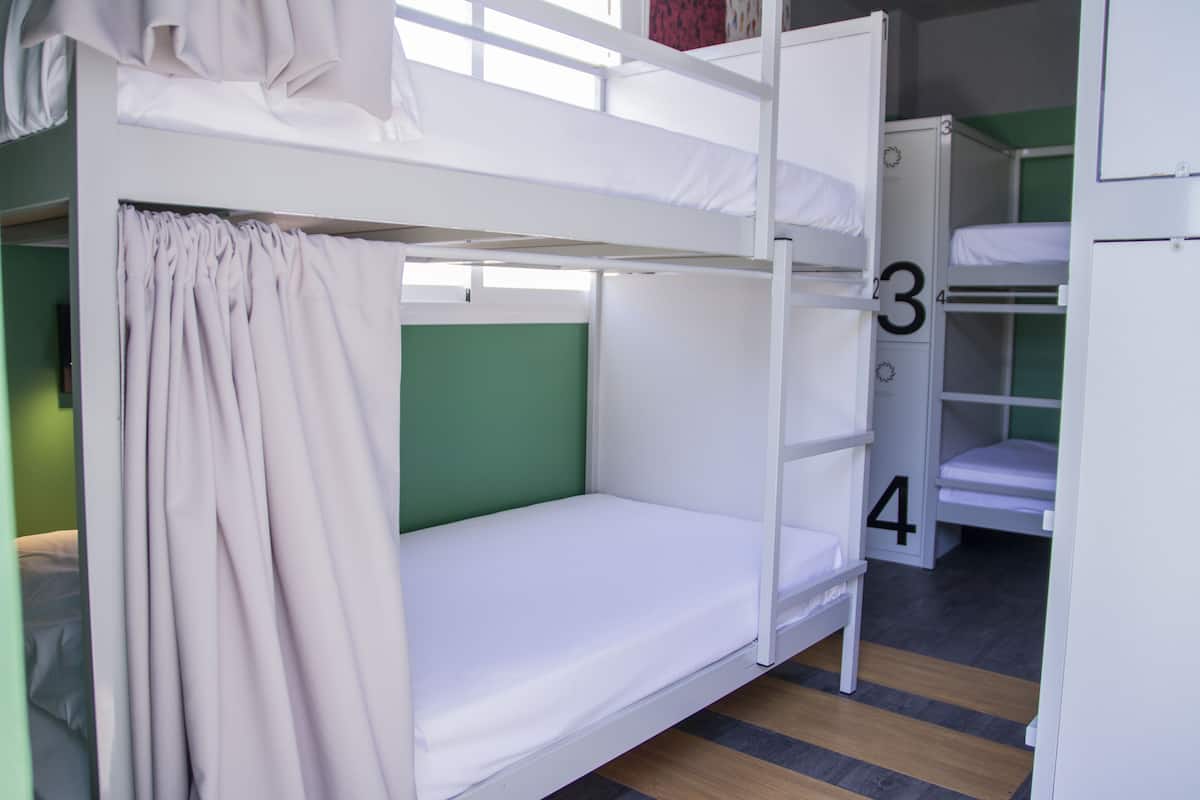 Uma cama box com cortina, parede verde e número 3.