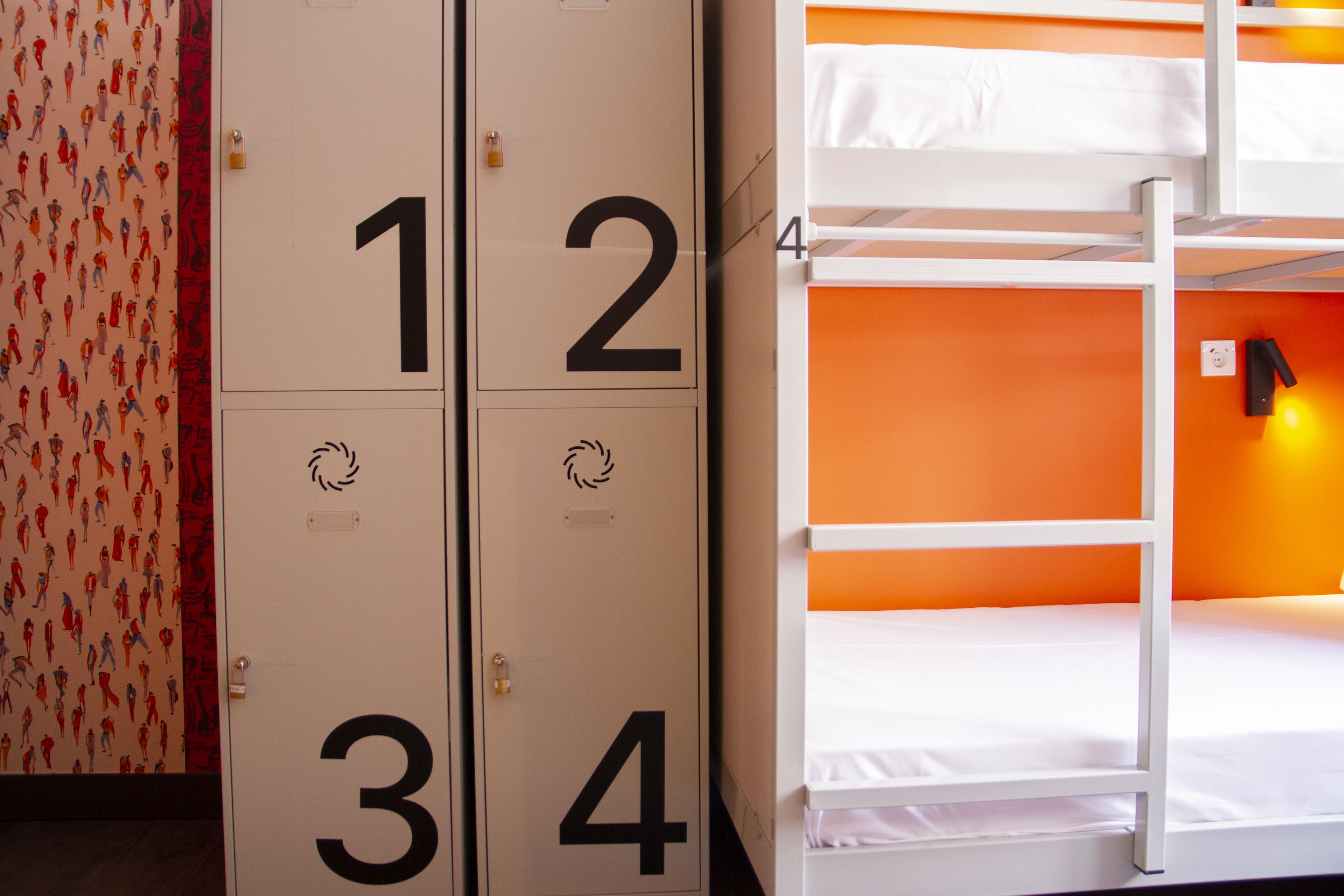 Una habitación con literas, una puerta numerada y un papel tapiz estampado.