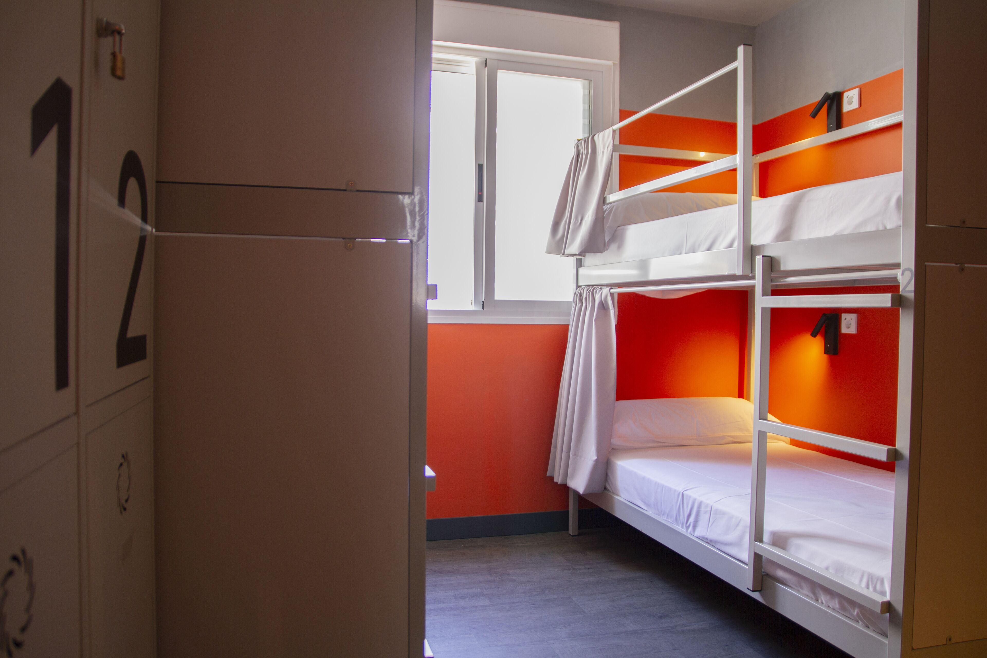 Un dormitorio con literas, una ventana y una puerta con números.