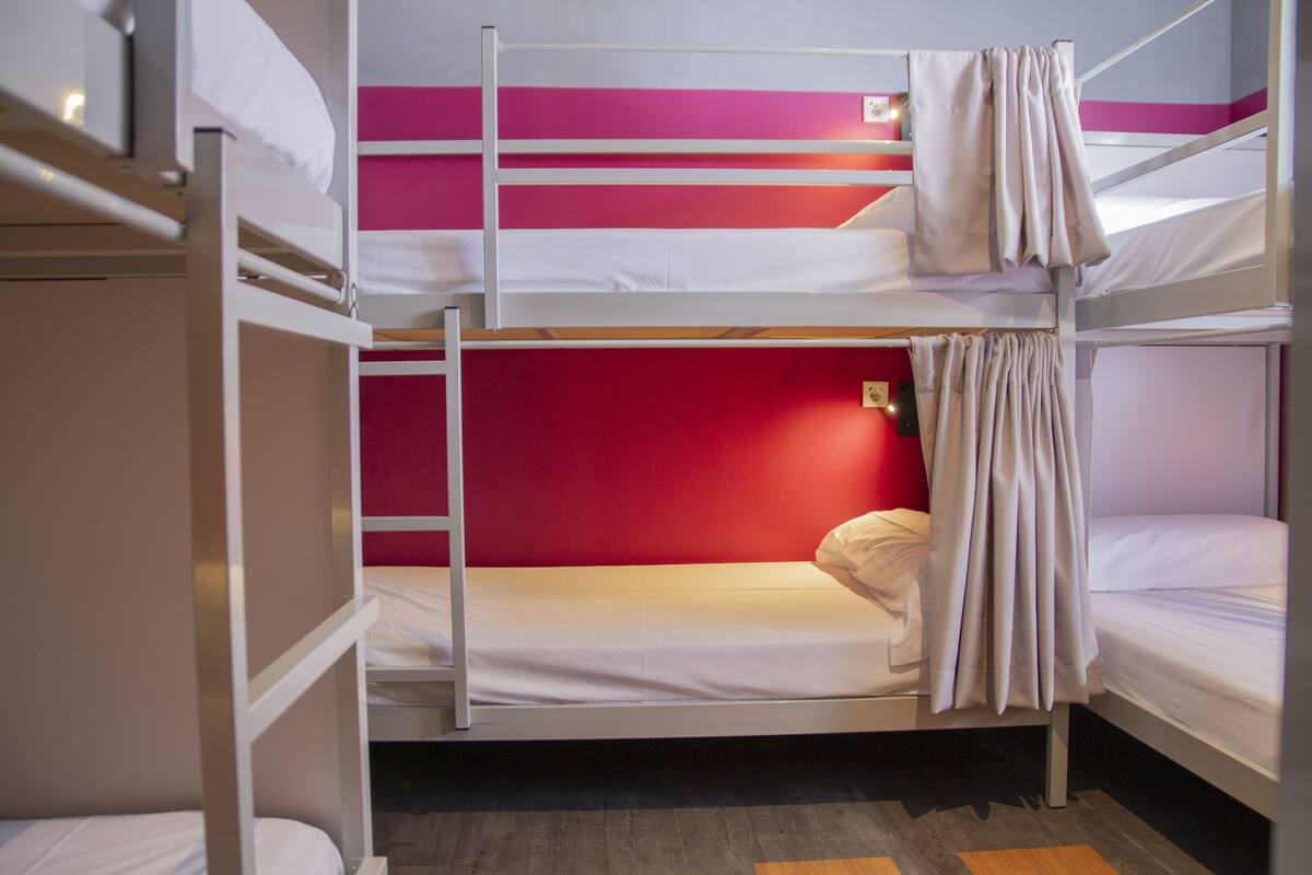 Quarto com beliche, parede vermelha e piso de madeira.