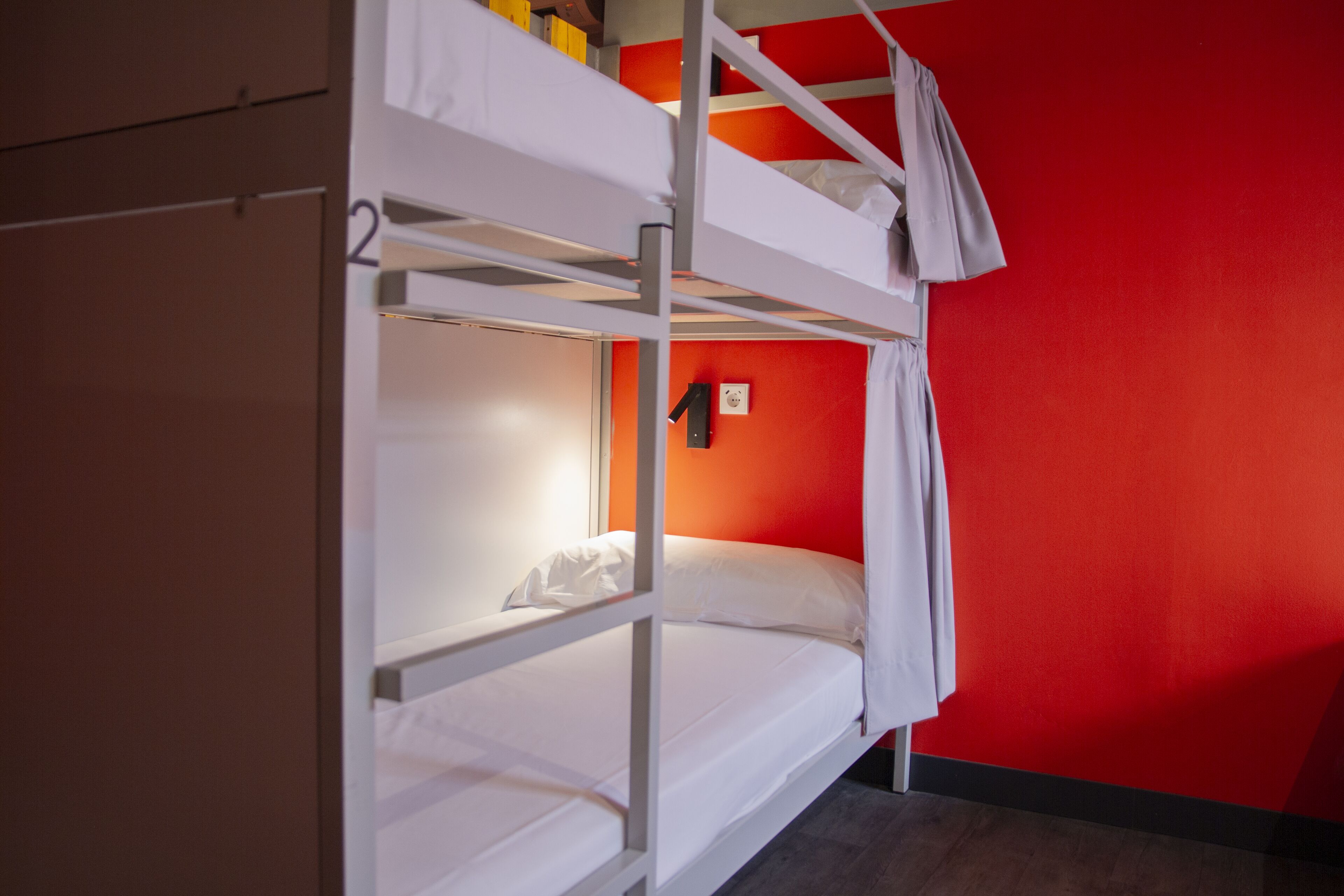 A bunk bed room with a red wall and a white ceiling.