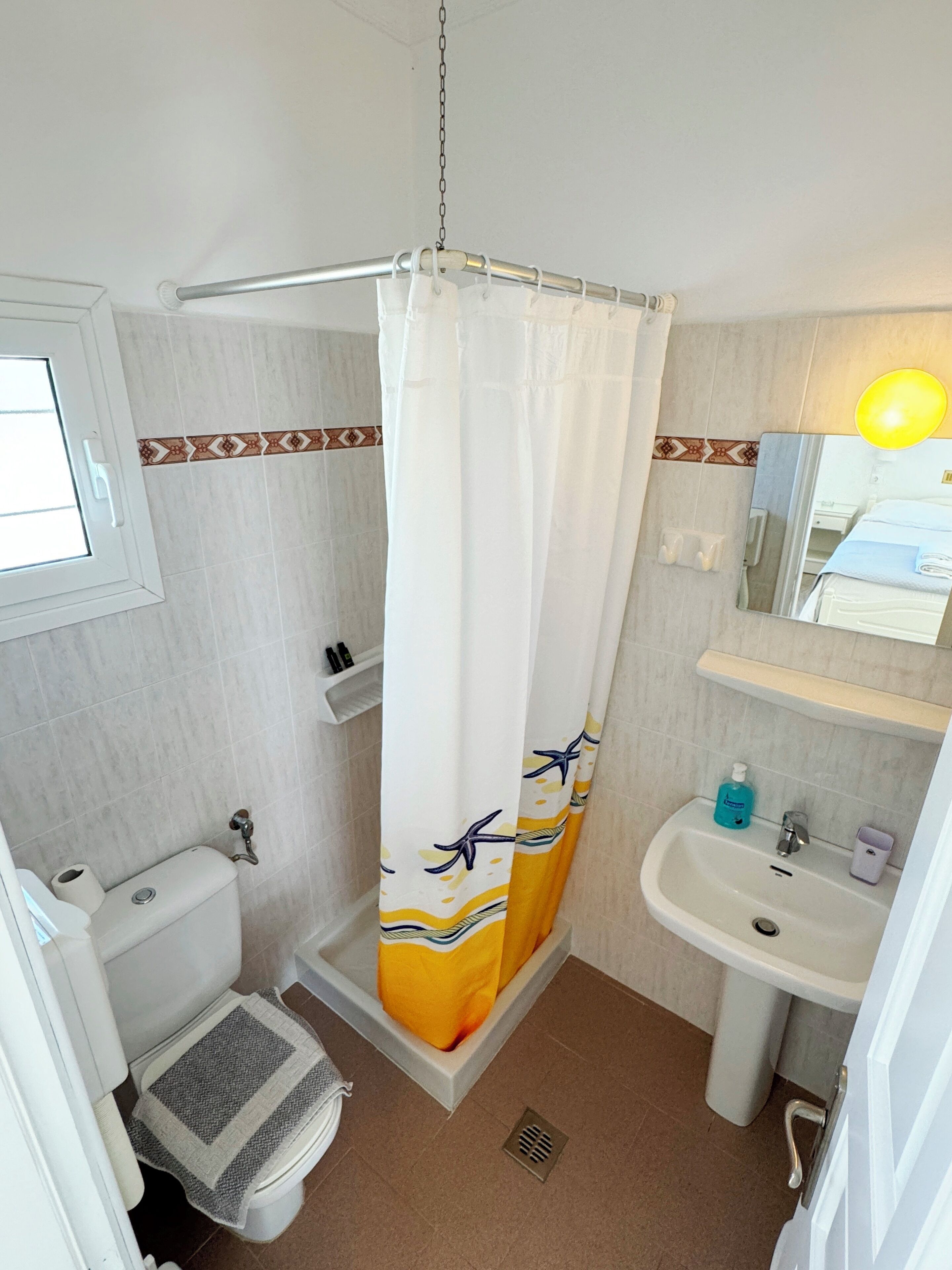 A bathroom with a shower curtain, toilet, sink, and a mirror.