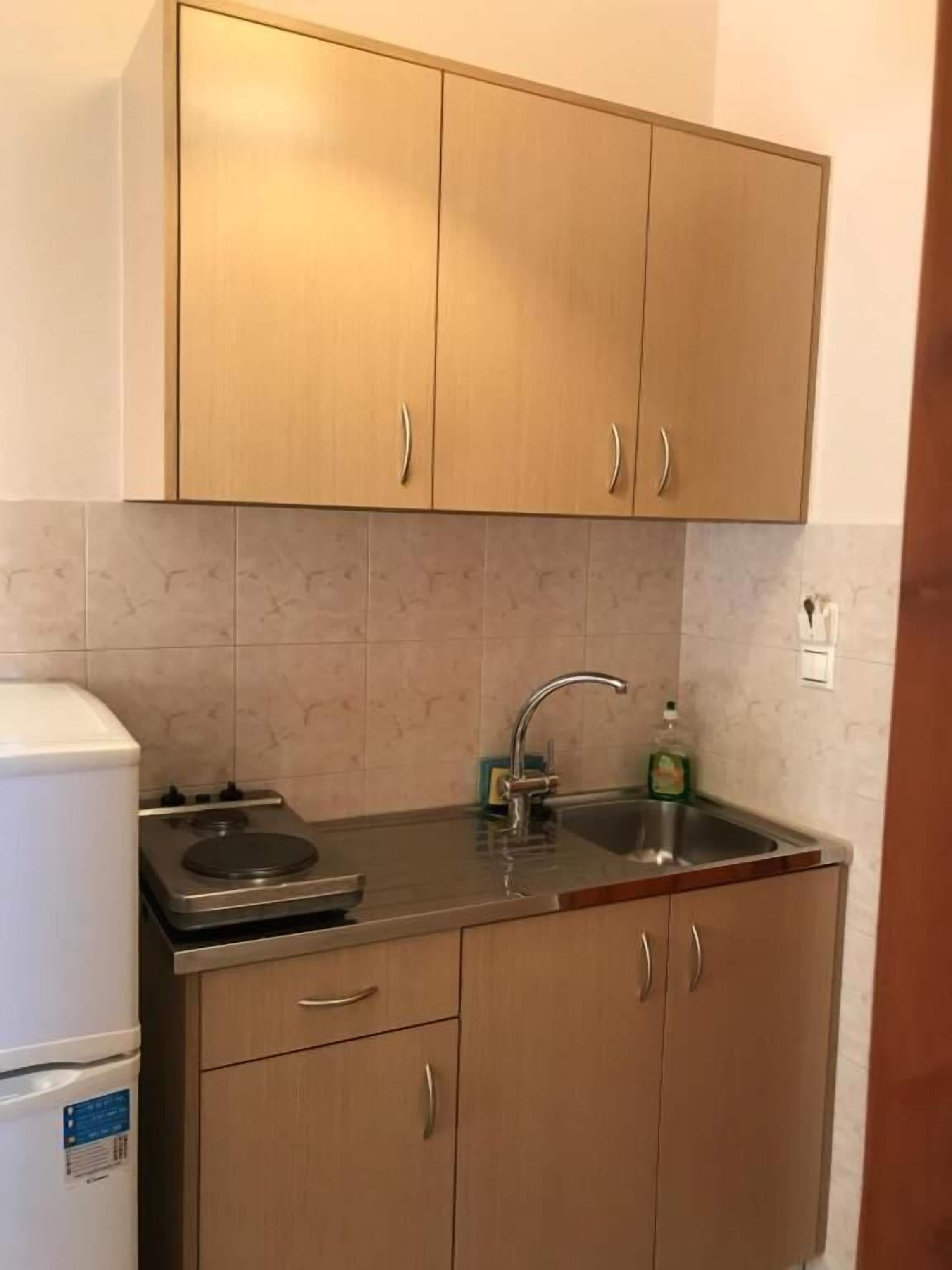 A compact kitchen with wooden cabinets, a stainless steel sink, and a white refrigerator.
