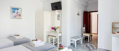 A hotel room with two beds, a desk, a chair, a TV, and a bathroom visible through an open door.