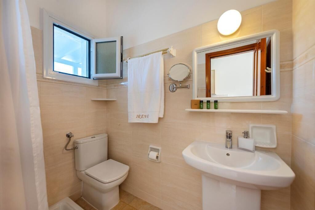 Un baño con inodoro, lavabo, espejo y ventana.