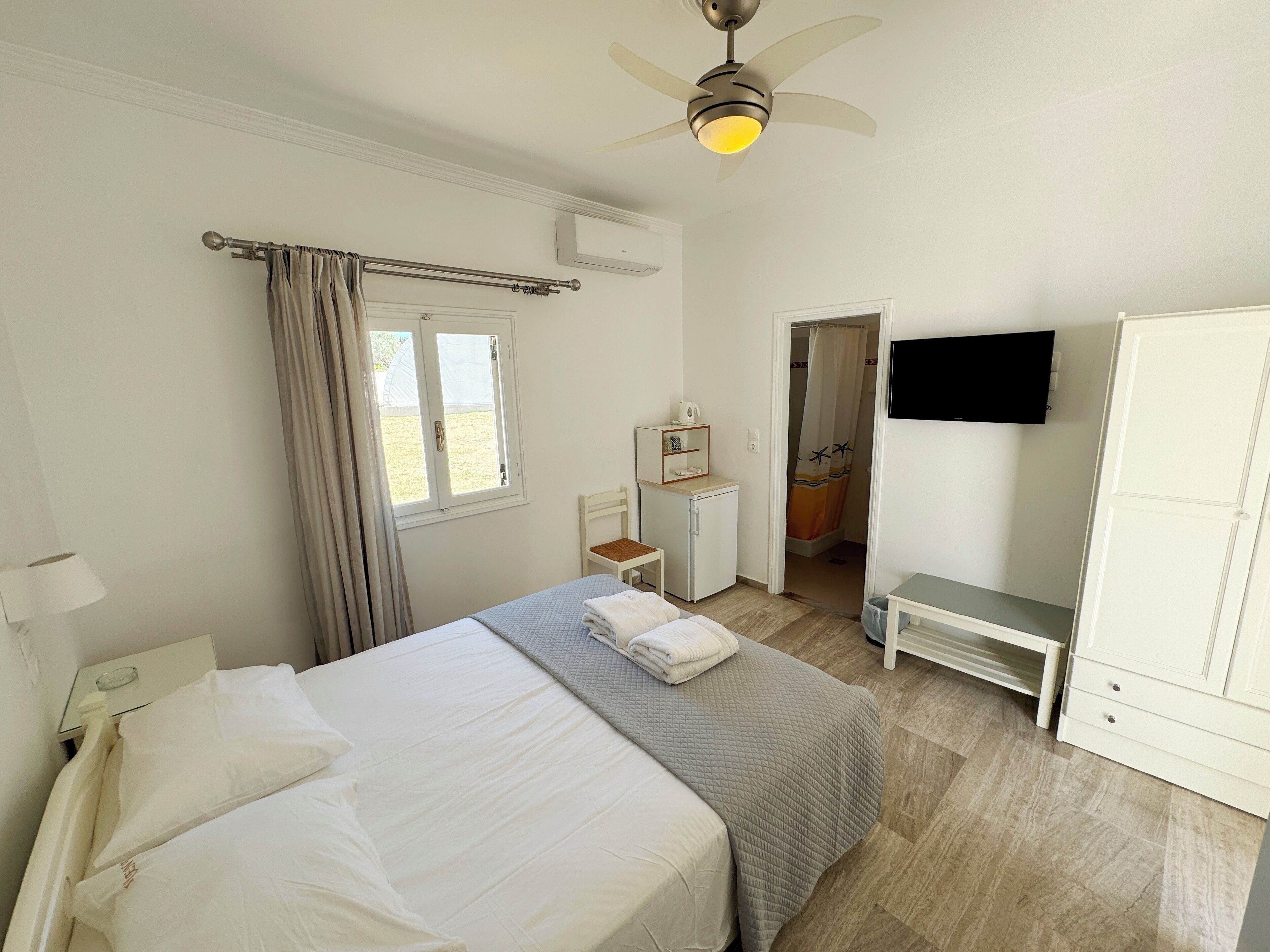 Une chambre d’hôtel équipée d’un lit, d’un bureau, d’une télévision et d’une armoire.