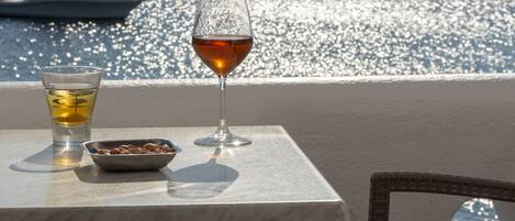 A table with a glass of wine and a small dish, overlooking a marina with boats.