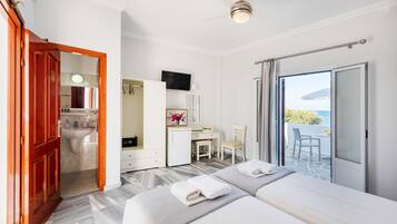 Ein Hotelzimmer mit zwei Betten, einem Schreibtisch, einem Sessel, einem Fernseher und einem Balkon mit Blick.
