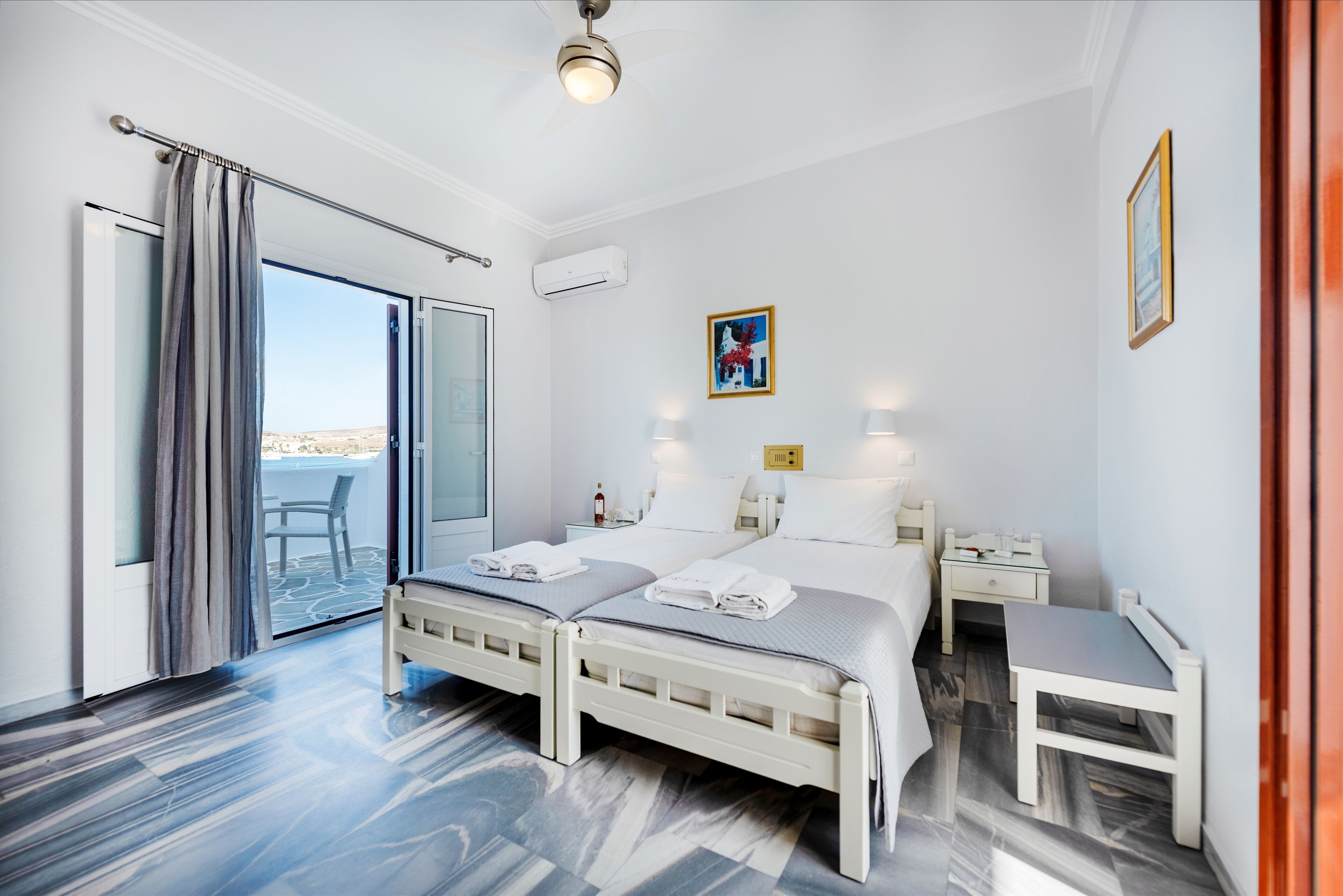 A hotel room with a bed, bedside tables, a chair, and a view through a glass door.