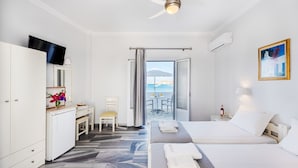 Ein Hotelzimmer mit Bett, Schreibtisch, Stuhl und Meerblick durch eine Glastür.