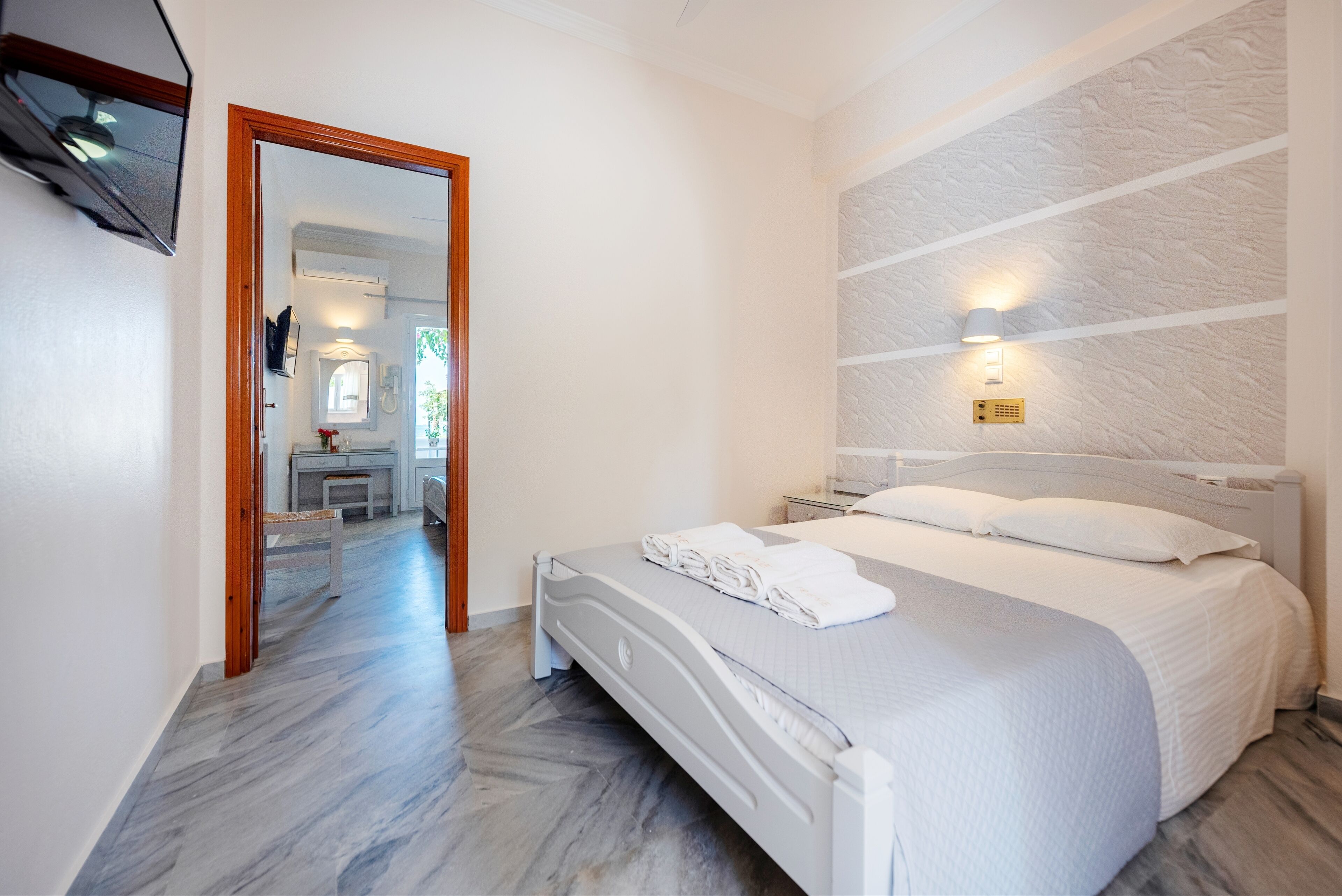 Un dormitorio con cama, mesita de noche, luz empotrada en la pared y espejo.