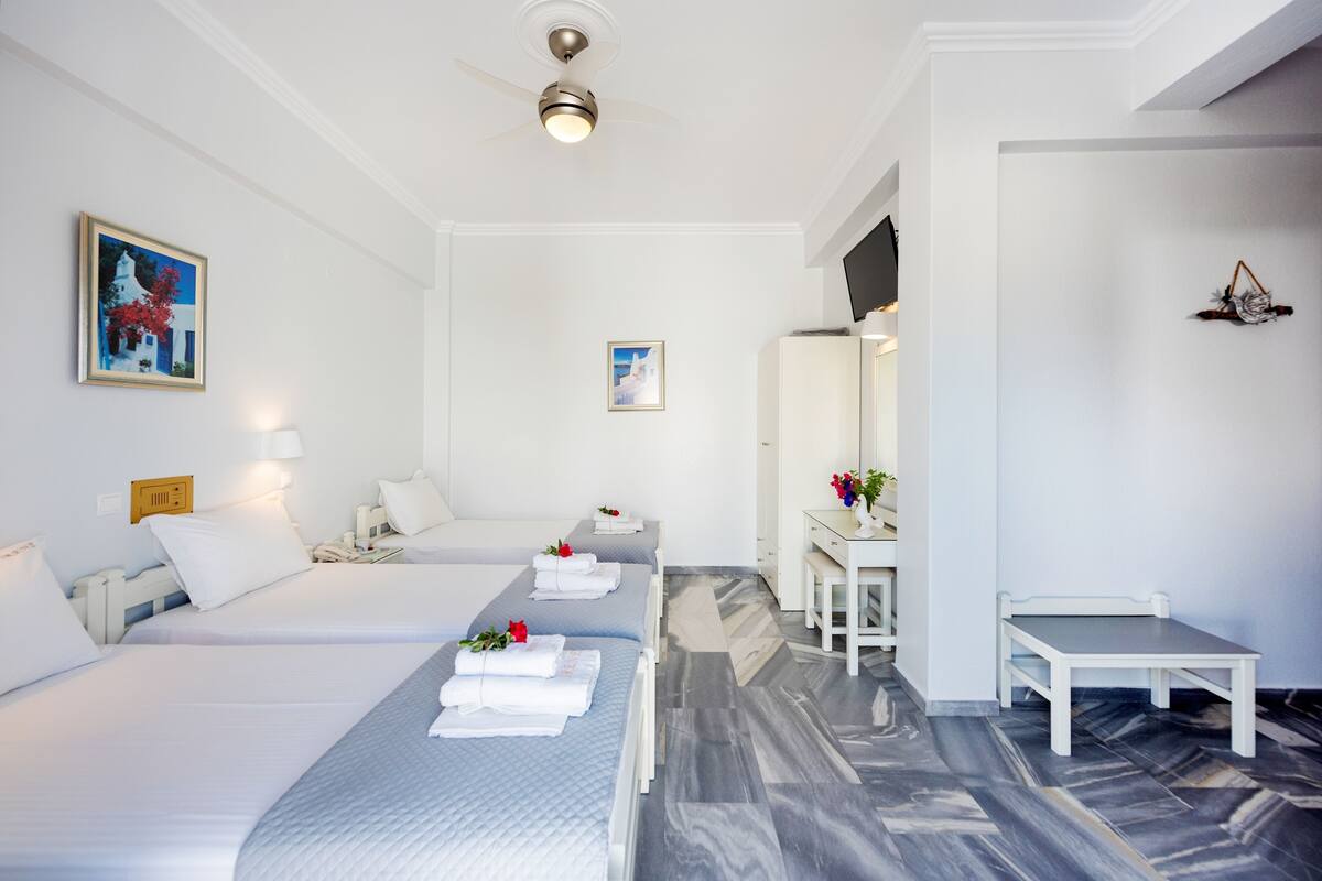 Una habitación de hotel con dos camas, un escritorio, una silla y un espejo.