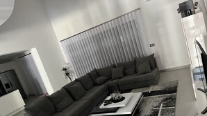 Un salon moderne avec un canapé d’angle, une table basse et un tapis à motifs.