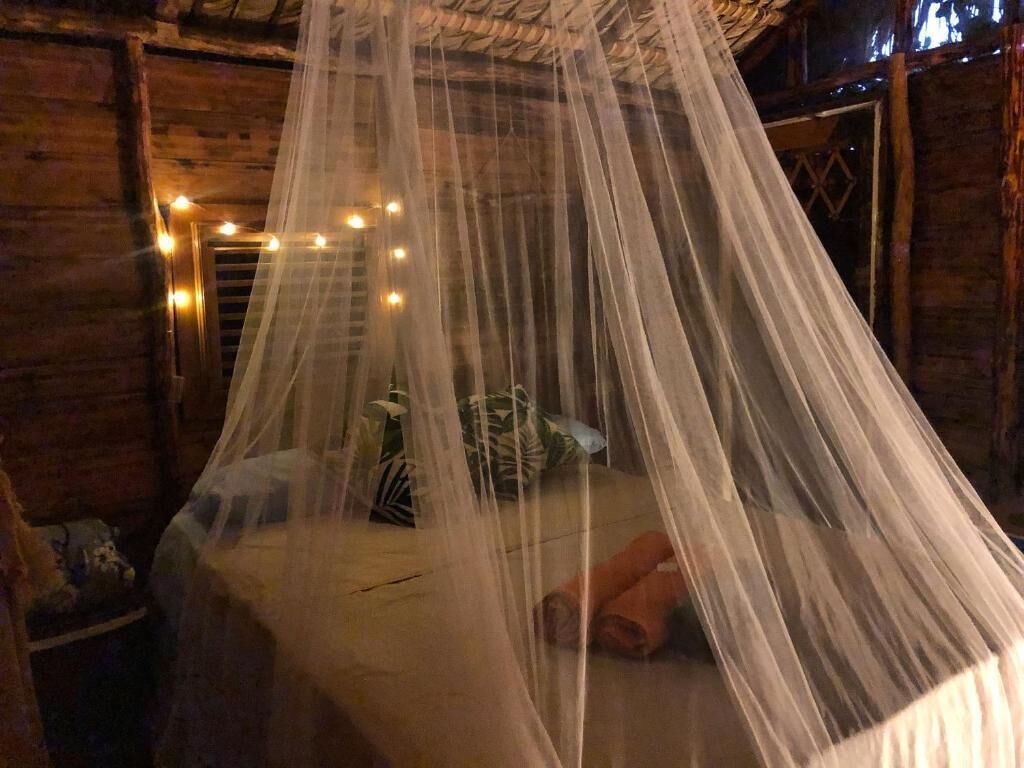 Una habitación con una cama bajo un dosel, paredes de madera y luces colgantes.