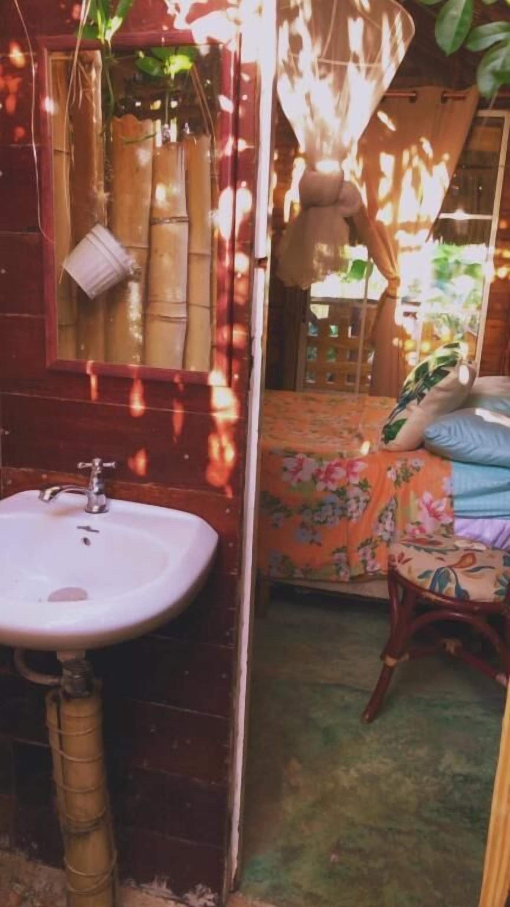 A bathroom with a sink, mirror, and bamboo blinds.