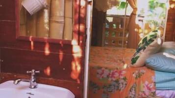 A bathroom with a sink, mirror, and bamboo blinds.