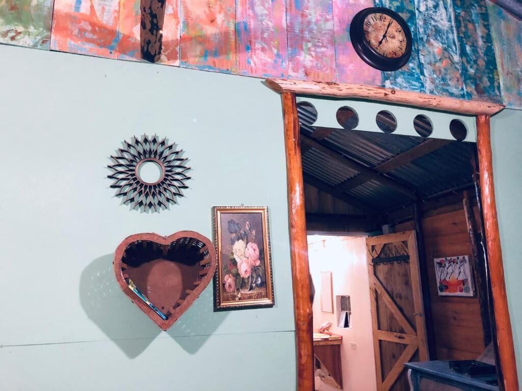Een rustiek interieur met een houten deur, een wandklok, een zondecoratie en een lijst met een afbeelding.