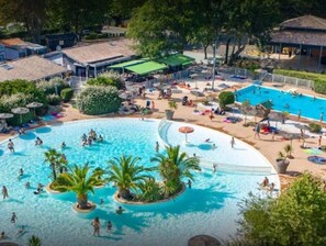 Ein großer Pool im Freien, umgeben von Palmen und schattigen Bereichen.