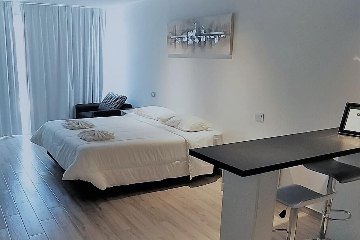 Une chambre d’hôtel moderne, équipée d’un lit, d’un bureau et d’une chaise.