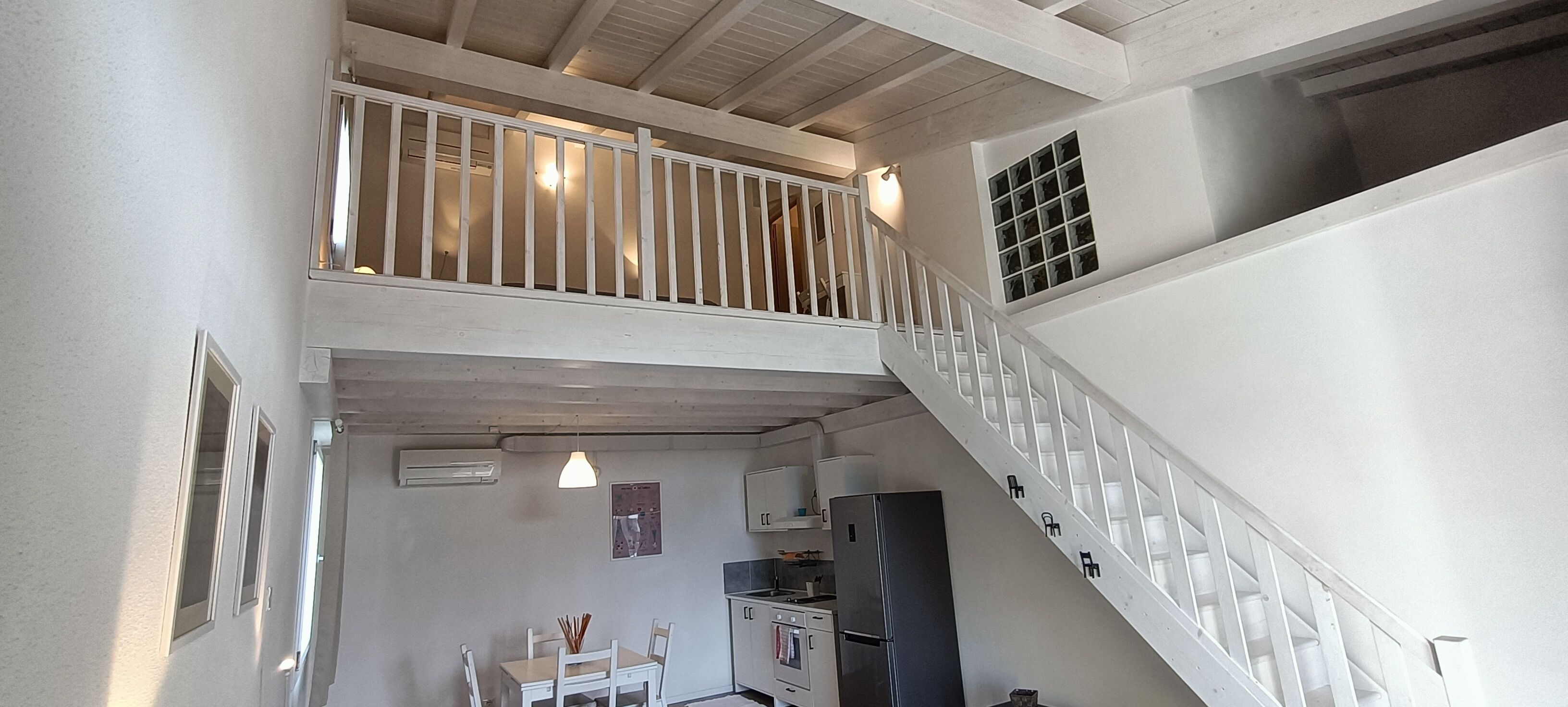 A multi-level interior with a staircase, a dining area, and a kitchen.
