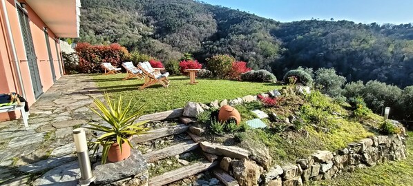 A garden with lounge chairs, a stone pathway, and a view of a mountainous landscape. - Orto dei Rolli (Moneglia)