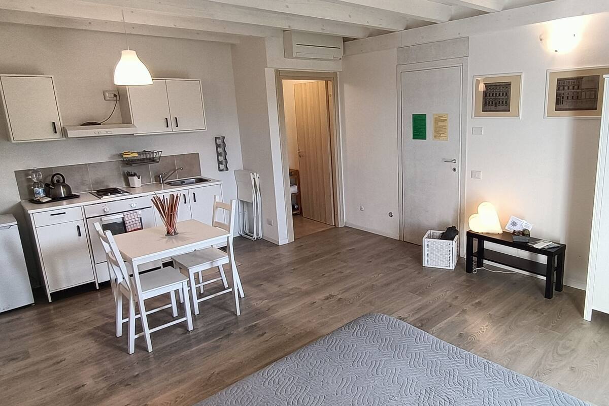A compact living space with a kitchenette, a dining area, a bed, and a wardrobe.