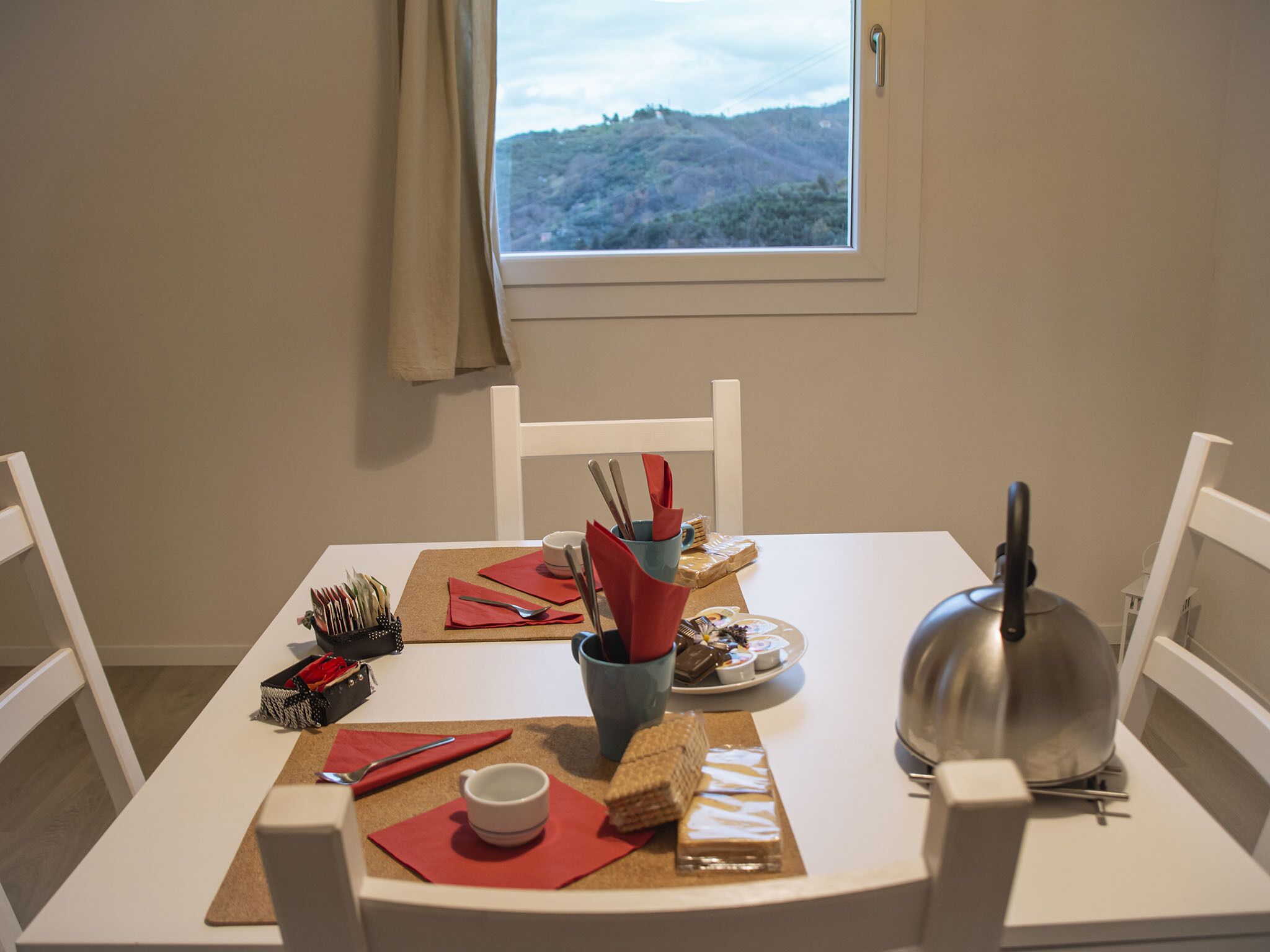 A dining table set with a teapot, cups, plates, and cutlery.