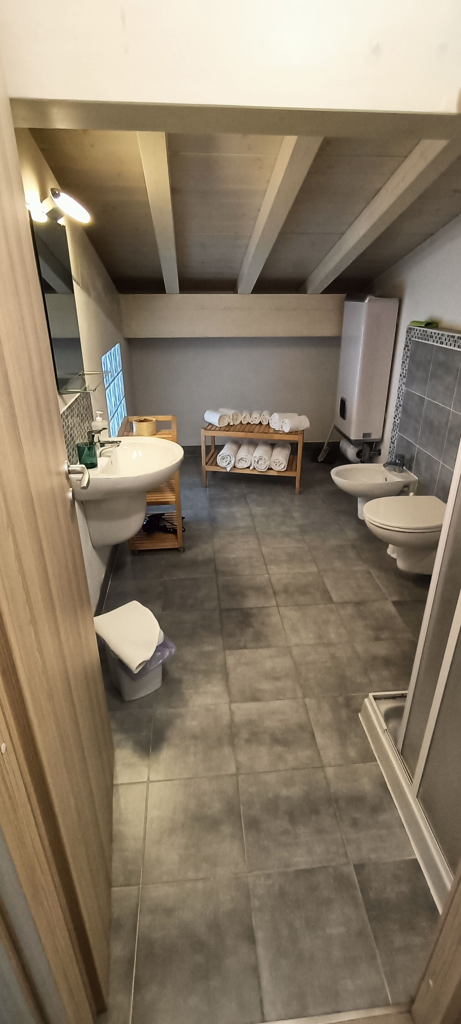 A modern bathroom with a large sink, two toilets, a shower, and a towel rack.