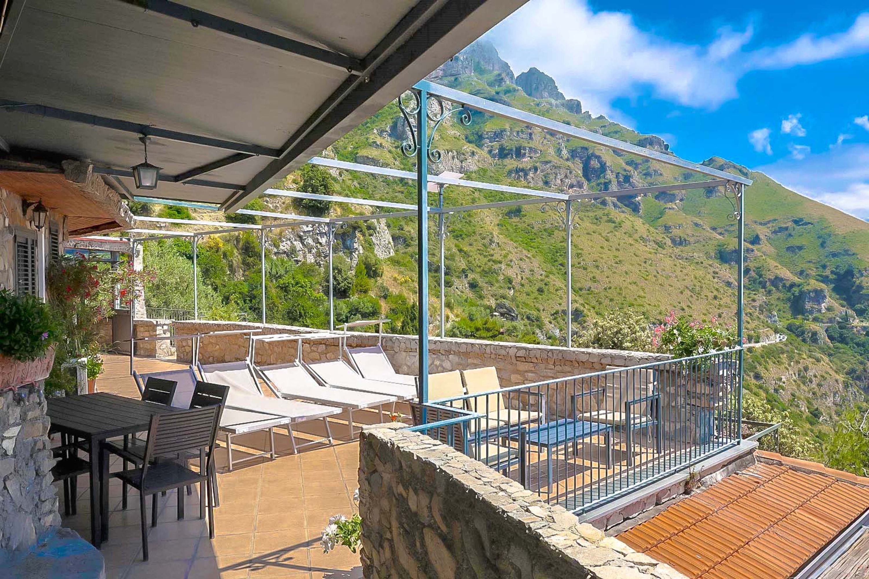 Eine Terrasse mit Sitzgelegenheiten und Blick auf eine Berglandschaft.