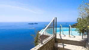 A stone staircase leading to a pool with a clear view of the sea and distant islands. - Villa Vanessa in Positano (Vico Equense)