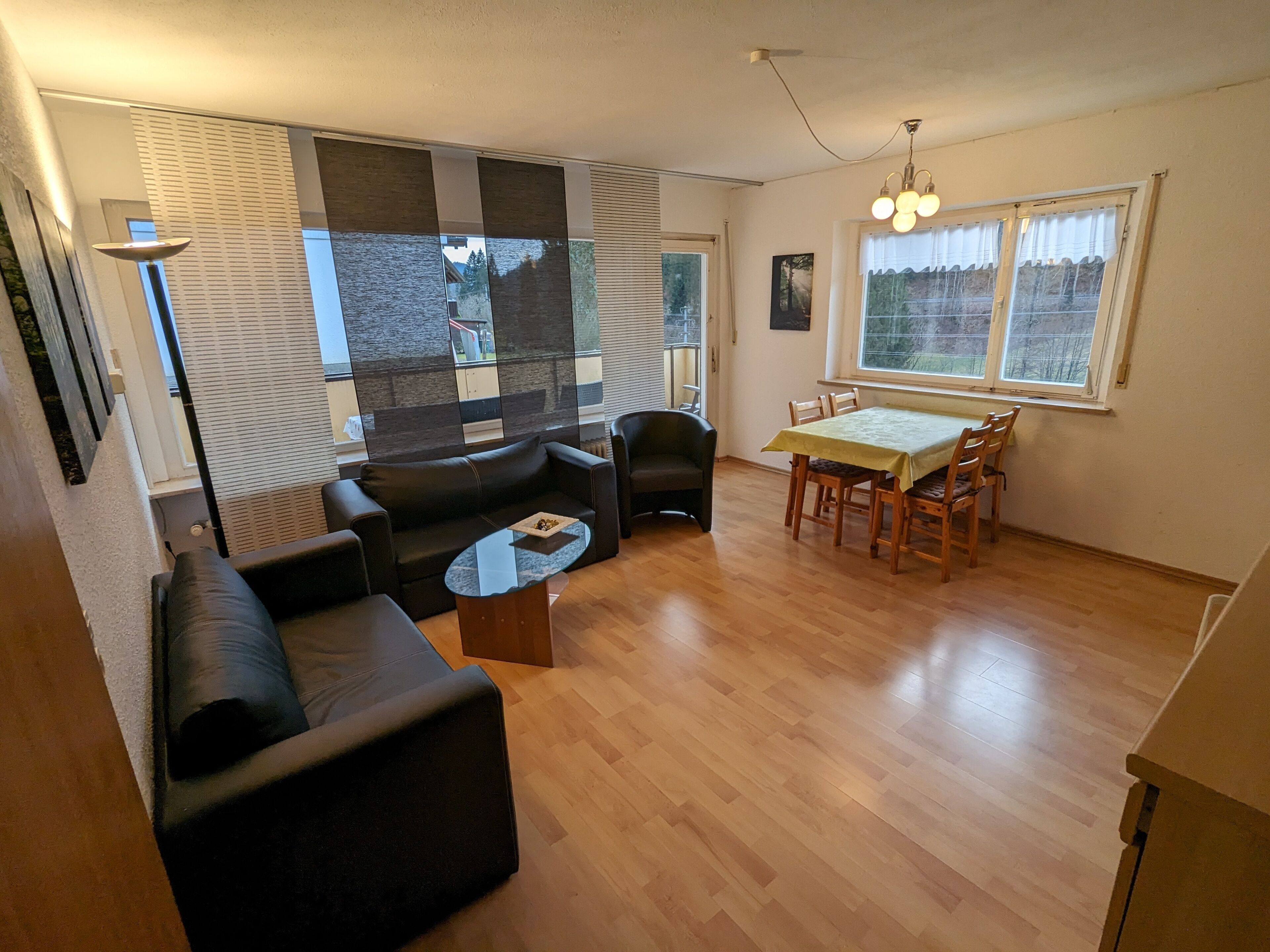 A living room with a sofa, a coffee table, and a dining area with a table and chairs.