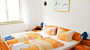 A double bed with a patterned blanket, two pillows, a bedside table with a lamp, and a framed picture on the wall. - Ferienwohnung Schwarzwaldsegen mit Balkon (Todtmoos)
