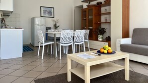 Een compacte leefruimte met een eethoek, een kitchenette en een zithoek met een bank.