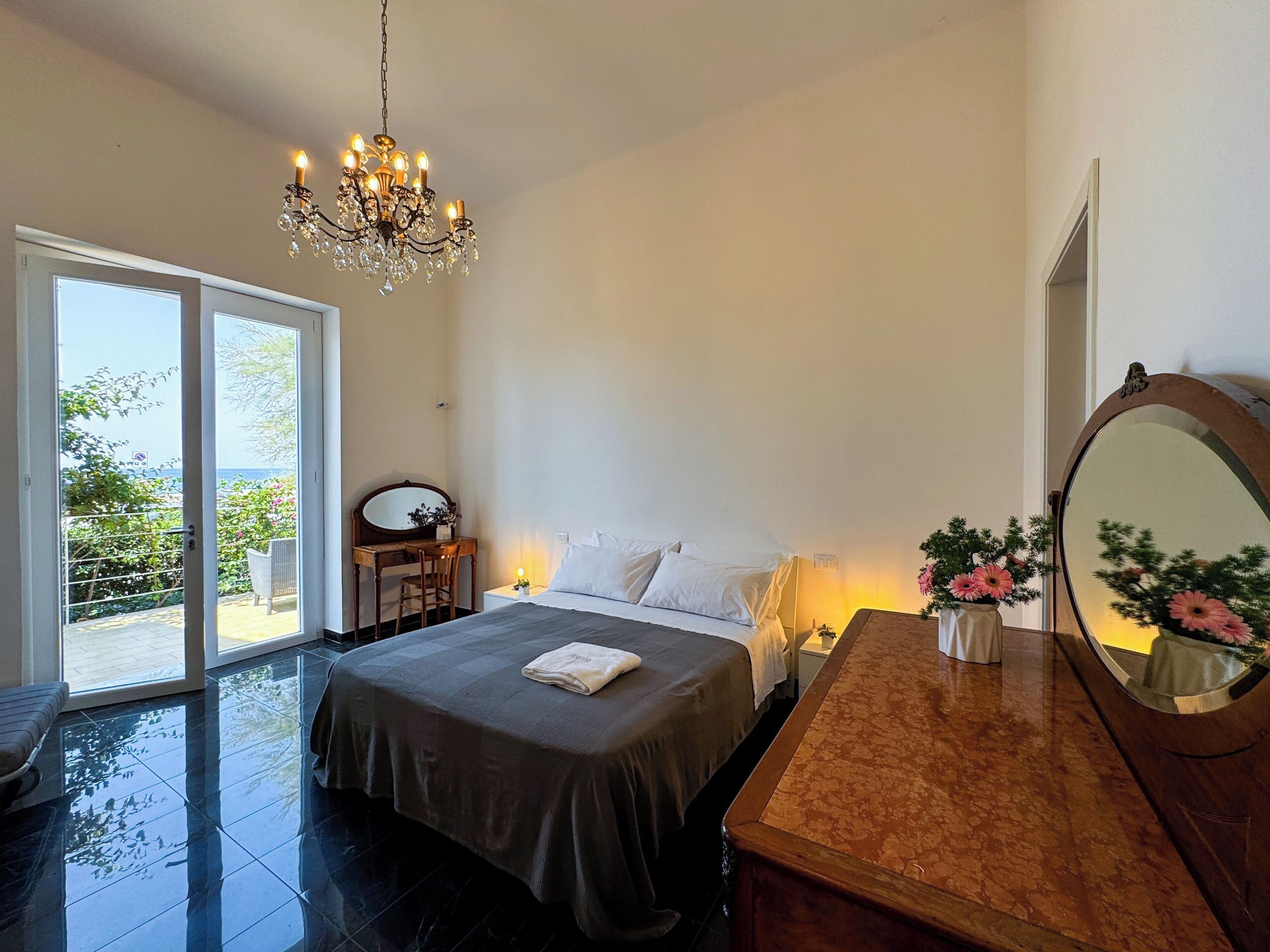 A bedroom with a bed, a nightstand, a dresser, a mirror, and a chandelier.