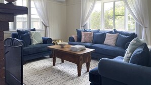 Ein Wohnzimmer mit blauem Sofa, einem Holztisch und einem gemusterten Teppich.