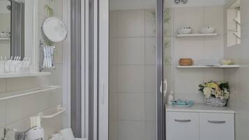 A modern bathroom with a shower, two sinks, a mirror, and shelves with toiletries.