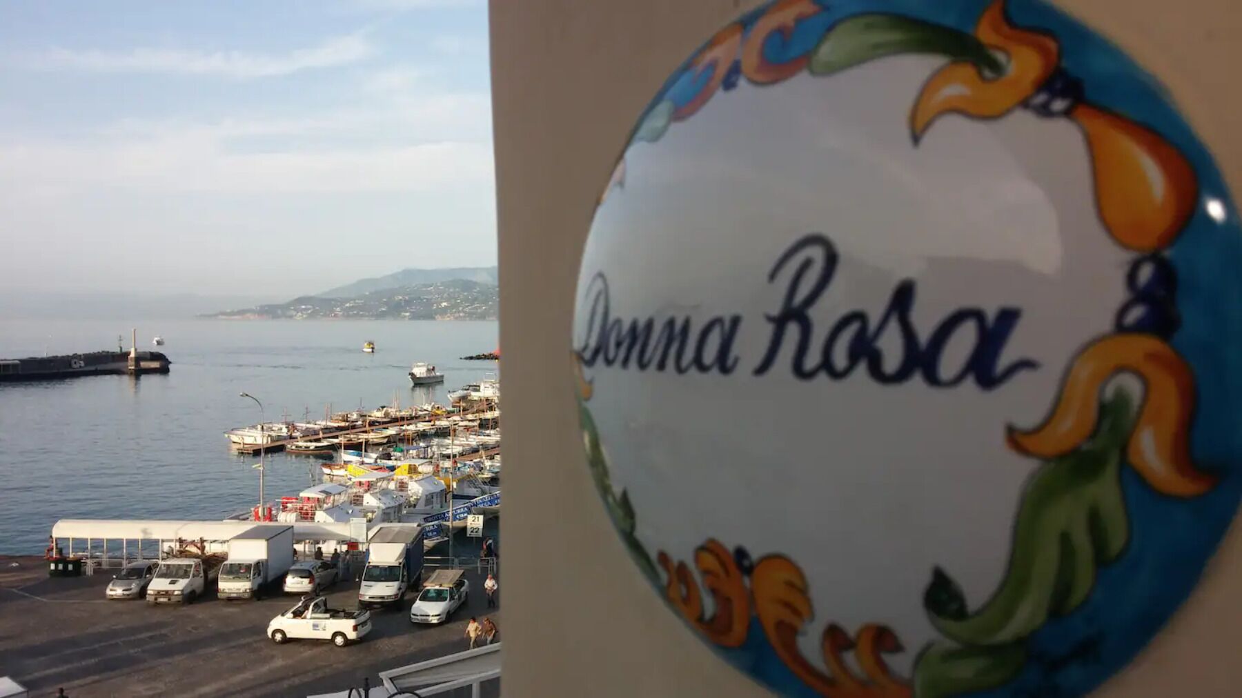 Ein Yachthafen mit Booten und Fahrzeugen, und ein Schild mit der Aufschrift 'Donna Rosa'.