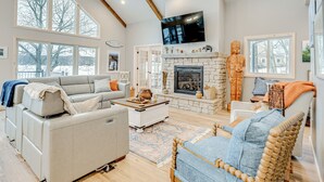 Un salón amplio con chimenea, ventanas grandes y un techo alto.