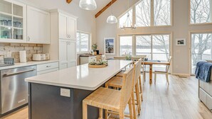 Una cocina moderna con una isla grande, sillas de madera y un comedor con vista al exterior.
