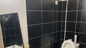 A bathroom with a white sink, mirror, and toilet. The walls are tiled in black and white. - Appartement T1 Vieux Port Opera (Marseille)