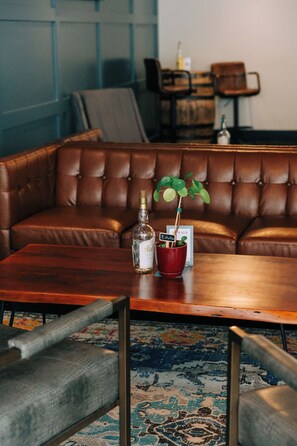 Un canapé en cuir marron, une table basse en bois et un pot de fleurs rouge contenant une plante verte.